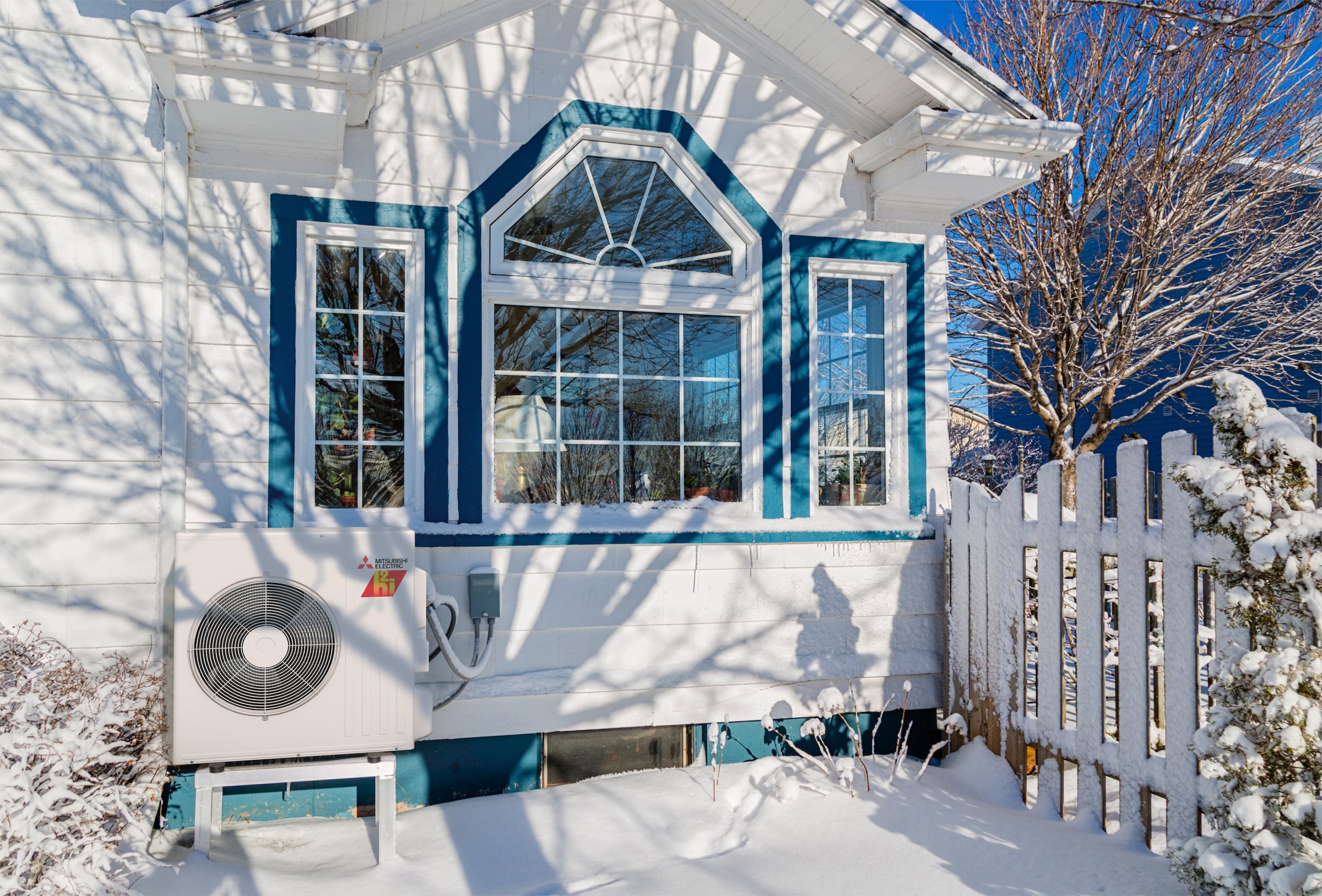 Mitsubishi heat pump outside a white house in the middle of winter