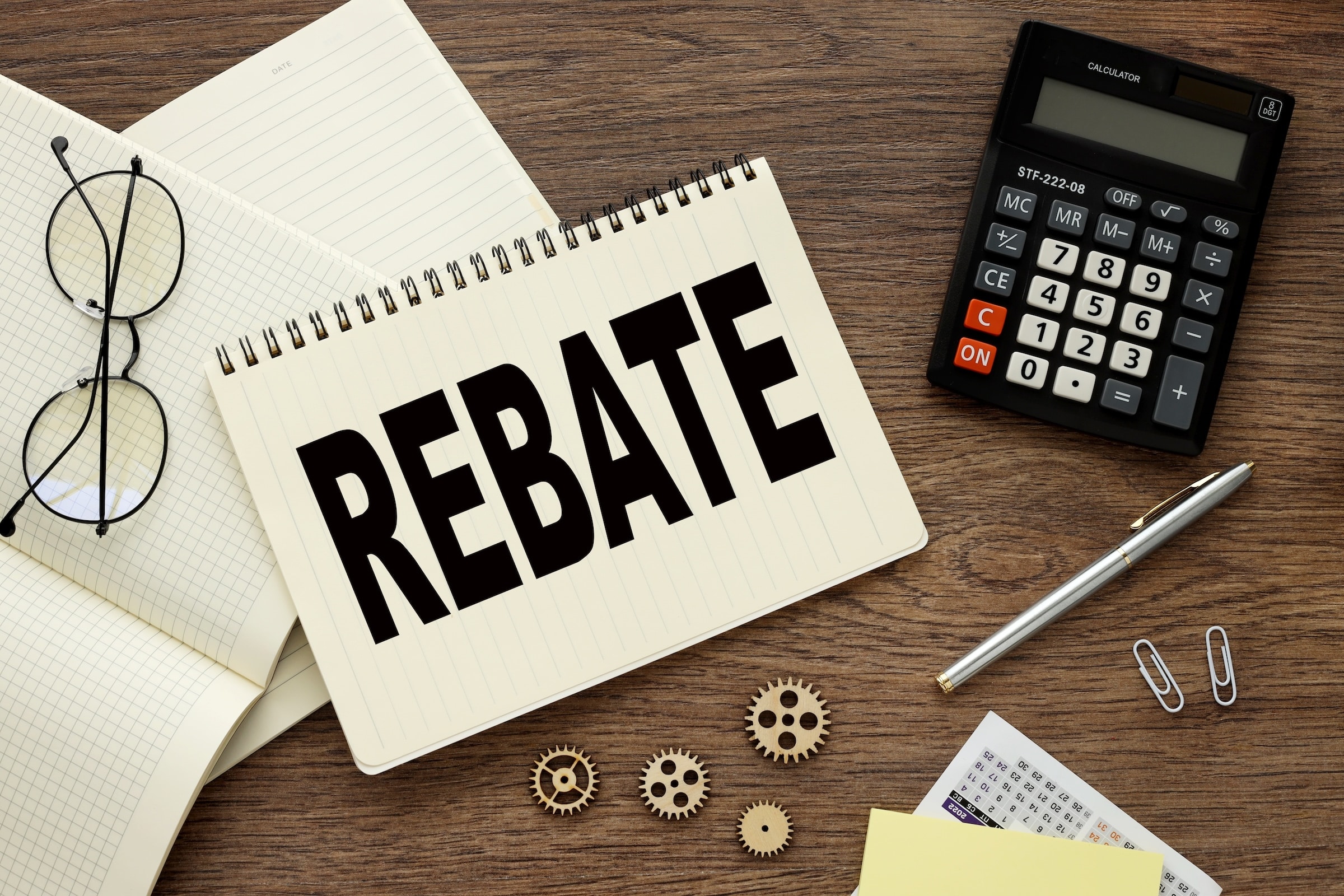 Desk with paper that says "REBATE", a calculator and a pen